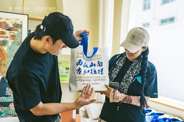 图为王子豪正在介绍印有科考之旅相关内容的挎包.jpg ""